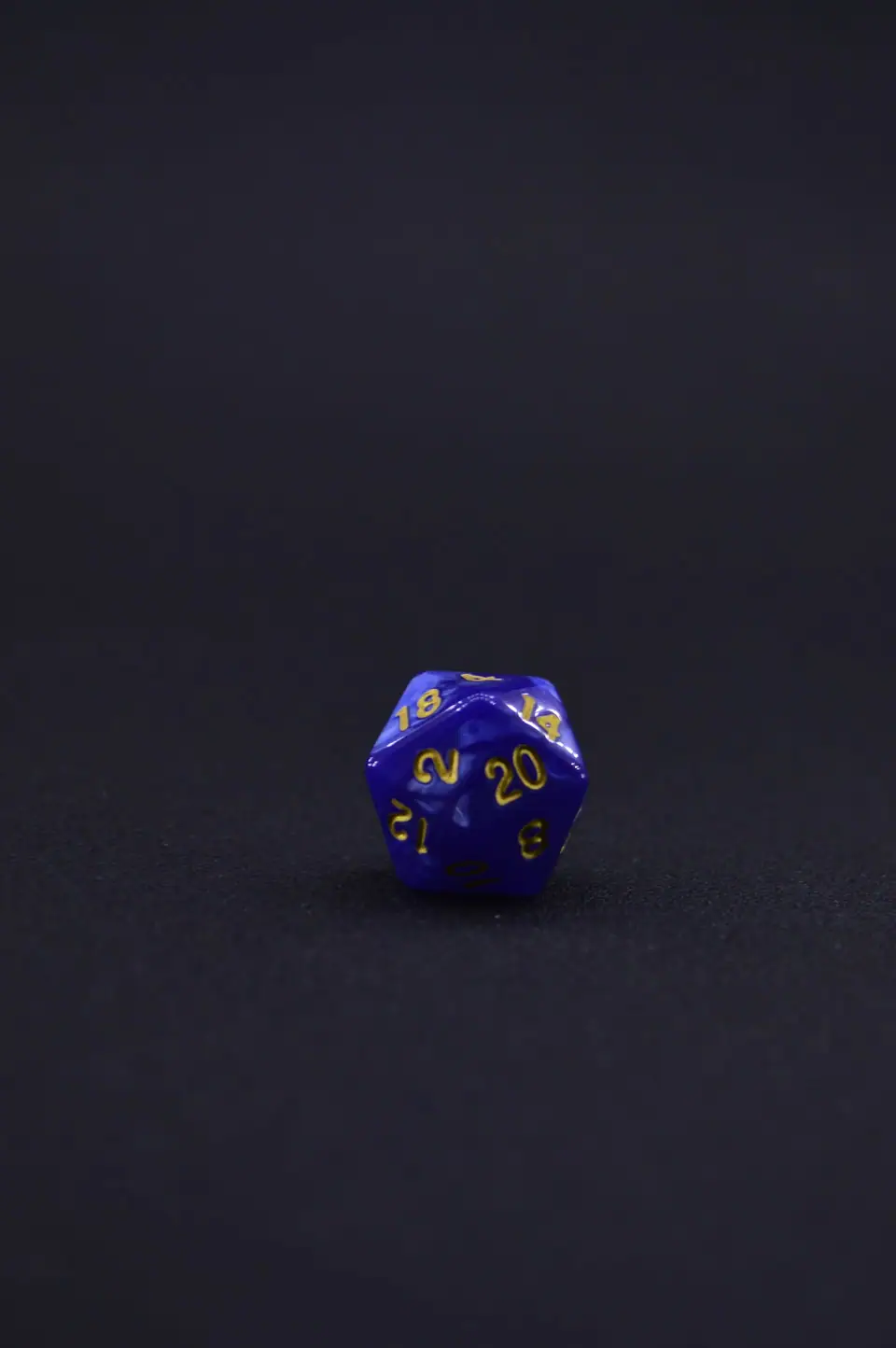 Close-up of a blue twenty-sided dice resting on a black background.